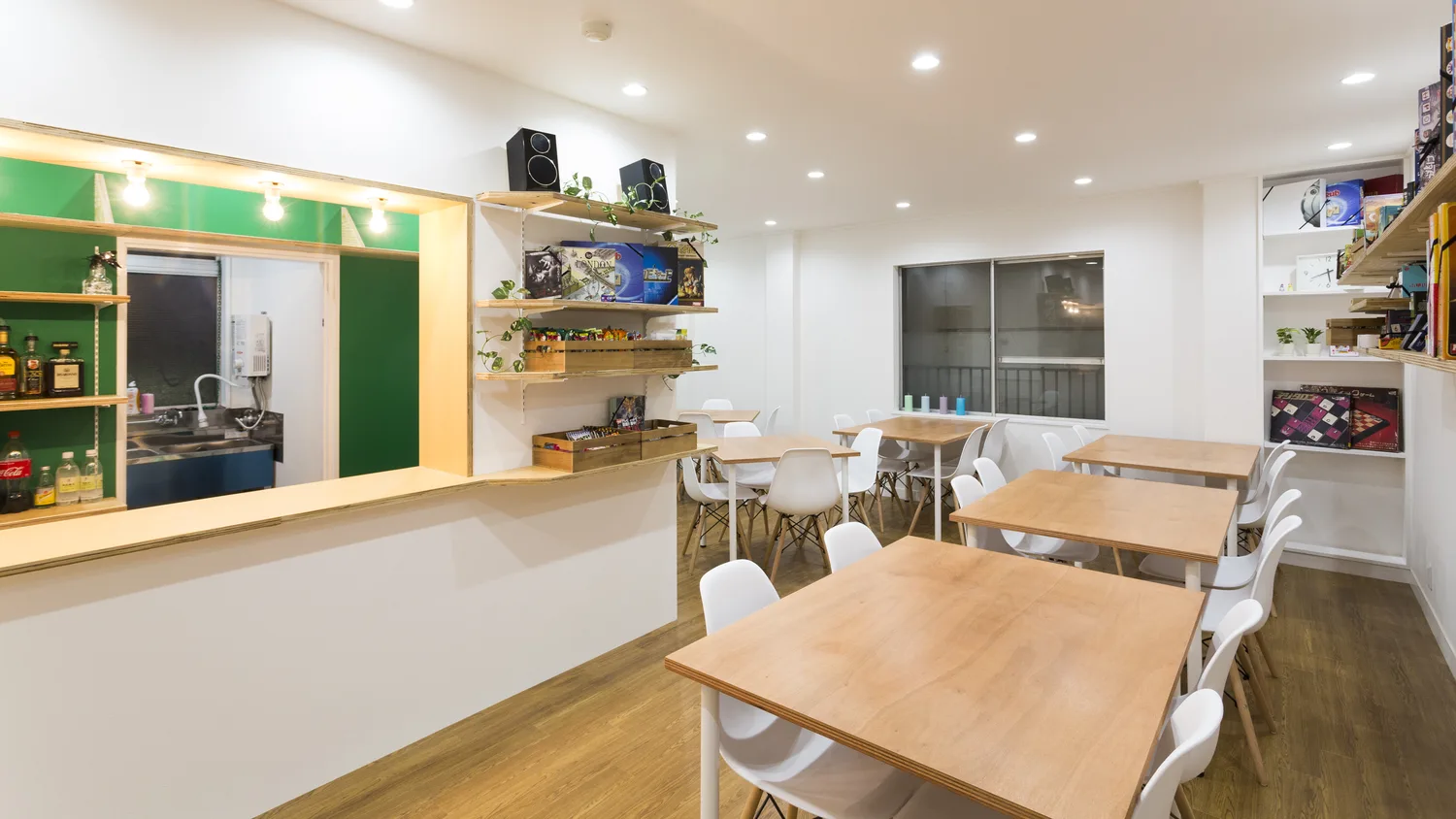 ボードゲームカフェ ロンドンの店内。木のテーブルと椅子、壁面にボードゲームの棚
